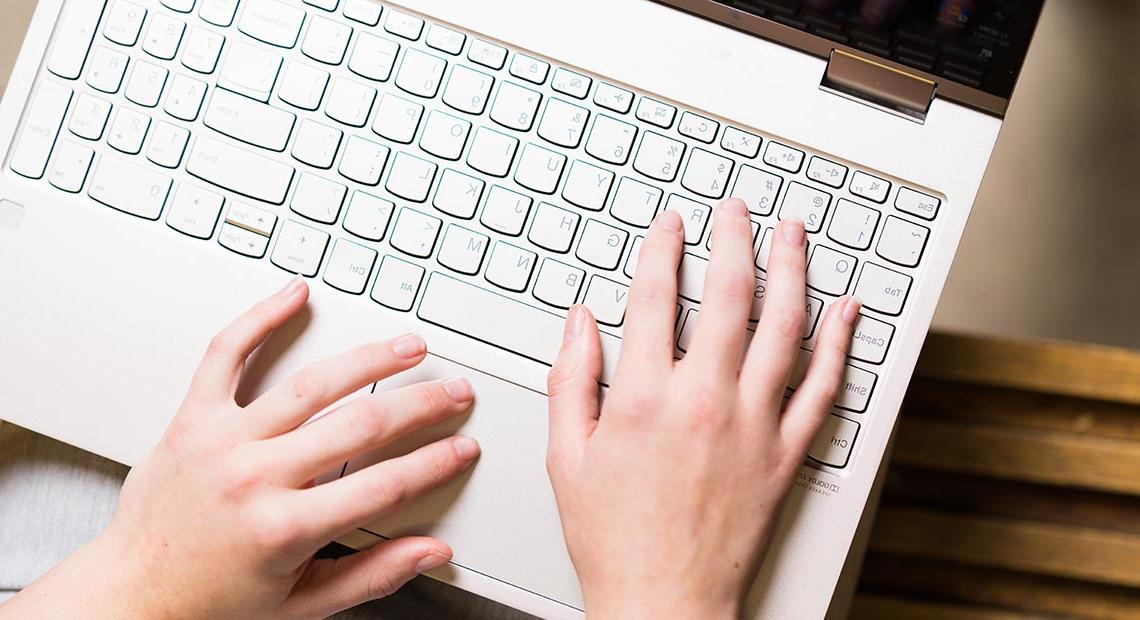 Hands typing on a laptop keyboard