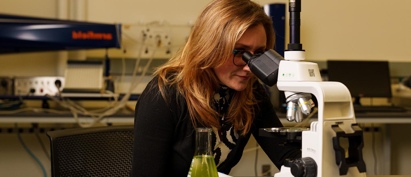 A woman looking into a microscope