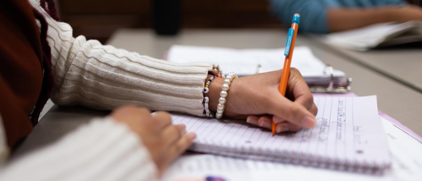 Hands writing in a notebook